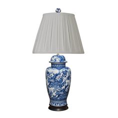 a blue and white vase with a lamp on it's side next to a light shade