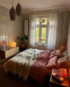 a bed room with a neatly made bed and two lamps hanging from the ceiling next to a window