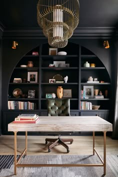 an office with black walls, leather chair and bookshelves in the background is a chandelier