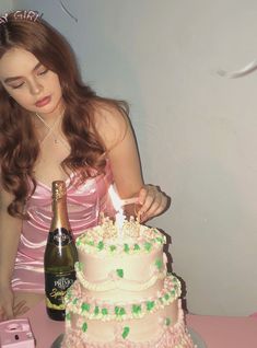 a woman in a pink dress is blowing out the candles on her birthday cake with a bottle of champagne