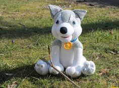 a stuffed dog sits in the grass with a stick