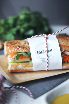 a sandwich wrapped in paper on top of a cutting board