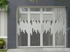 a large white gate with black bars on the top and bottom, in front of a gray building