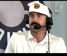 a man wearing a white hat and headphones in front of a wall with a logo on it