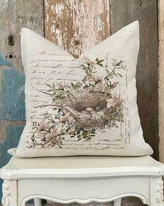 a white bench with a pillow on it and a bird's nest in the middle