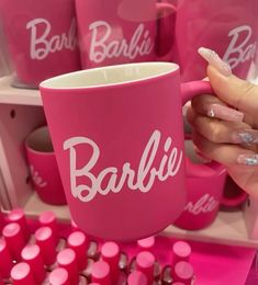 a person holding a pink coffee mug in front of some bottles