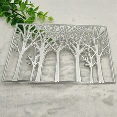 a metal cutting board with trees cut out of it and some leaves on the side