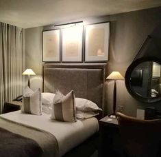 a hotel room with a bed, mirror and two lamps on either side of the bed