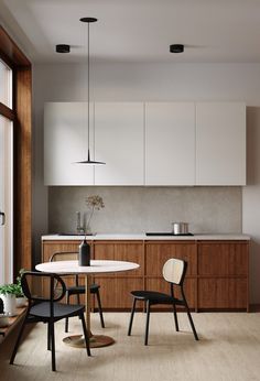 a kitchen with wooden cabinets and white counter tops next to a dining room table that has two chairs around it