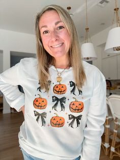 a woman wearing a white sweater with pumpkins on it