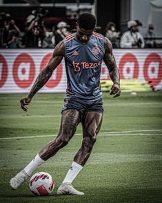 a man kicking a soccer ball on top of a field