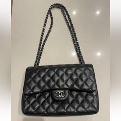 This Chanel Shoulder Bag Is A Timeless Classic, Crafted From Black Quilted Lambskin Leather With Silver Hardware Accents. The Authentic Bag Id# 19277509 The Bag Features A Rectangular Shape With A Turn Lock Closure And Double Handles For Easy Carrying. It Has A Large Size With A Depth Of 3.75 Inches, A Width Of 12 Inches, And A Height Of 8 Inches. The Bag Has Four Inside Pockets And One Outside Pocket, Providing Ample Space For Your Essentials. It Also Comes With A Chain Strap That Can Be Adjusted To A Drop Of 12.75 To 23.5 Inches. The Bag Is Adorned With Silver Stitching Accents And Chanel's Signature Burgundy Leather Lining. This Classic Double Flap Shoulder Bag Is A Must-Have For High-end Bags With Cc Turnlock Closure And Double Flap, High-end Travel Shoulder Bag With Cc Turnlock Closure, Formal Soft Leather Bag With Double Flap, Luxury Office Bag With Double Flap, Everyday Clutch Bag With Cc Turnlock Closure, Clutch Bags With Cc Turnlock Closure For Everyday, Elegant Double Flap Bag With Dust Bag Included, Cc Turnlock Clutch Bag, Luxury Double Flap Business Bags