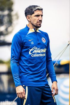 a man standing on top of a soccer field wearing a blue shirt and yellow shorts