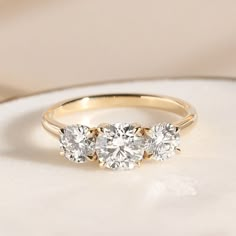 three stone diamond ring sitting on top of a table