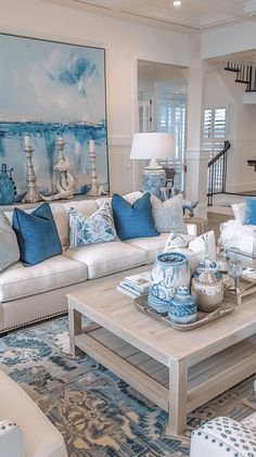 a living room filled with white furniture and blue pillows on top of it's couches