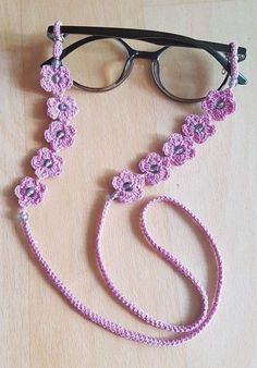 a pink crocheted lanyard with eyeglasses on the side and a pair of glasses