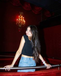 a young woman standing on top of a red carpeted floor next to a chandelier