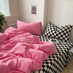 a bed with pink sheets and black and white checkered comforter in a bedroom