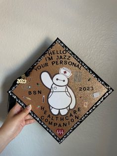 a person holding up a graduation cap with an image of a cartoon character on it