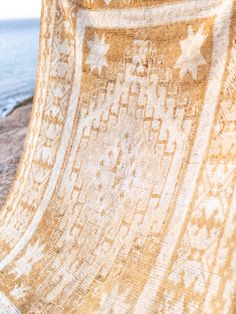 an orange and white blanket sitting on top of a sandy beach