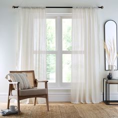 a chair sitting in front of a window next to a table with a mirror on it