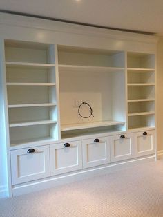 an empty room with white bookcases and carpeted flooring in the middle