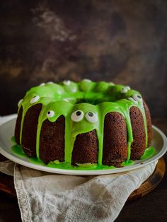 a bundt cake with green icing and eyes on the top is sitting on a plate