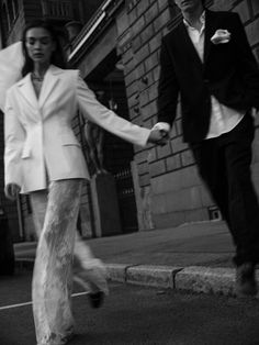 a man and woman walking down the street holding hands