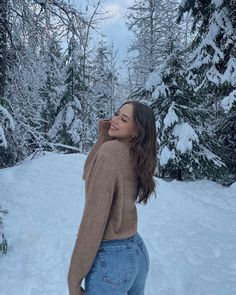 a woman is standing in the snow with her back to the camera and looking up