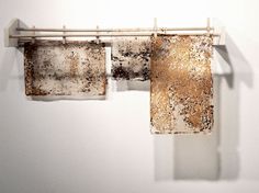 two pieces of paper hanging from a clothes line on a white wall with brown stains