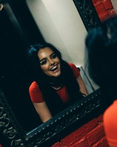 a woman smiling in front of a mirror