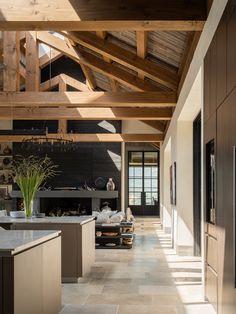 an open kitchen and living room with wood beams on the ceiling, tile flooring