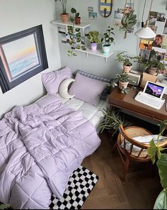 a bedroom with a bed, desk and plants