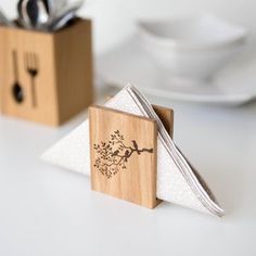 the napkin holder is made out of wood and has a tree on it with leaves