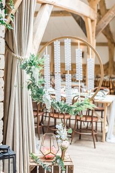 a wedding table with seating cards hanging from it's centerpieces and greenery