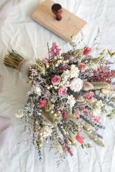 a bouquet of flowers sitting on top of a white sheet next to a wooden stamp