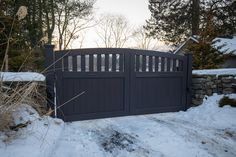 a wooden gate in the snow near some trees