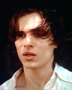 a close up of a person wearing a white shirt and hair in the middle of his face