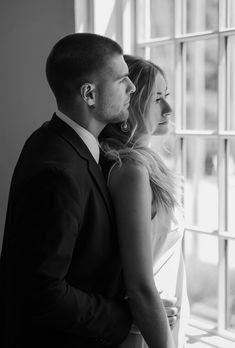 a man and woman standing in front of a window