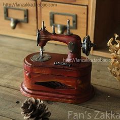 an old sewing machine sitting on top of a wooden table next to a pine cone