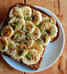 a piece of bread with bananas and pistachios on it sitting on a plate