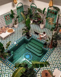 an indoor swimming pool surrounded by potted plants and other greenery on the floor