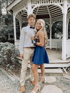 a man and woman standing in front of a gazebo with their arms around each other