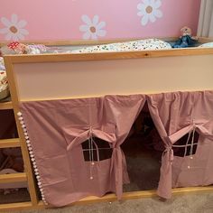 a bed with pink curtains and flowers on the wall next to a stuffed animal in a crib