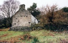 an old stone building sitting on top of a grass covered field next to some trees