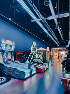 several arcade machines are lined up in a brightly lit room with neon lights on the ceiling