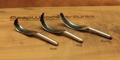 three metal spoons sitting on top of a wooden cutting board