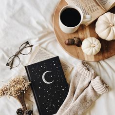 an open book on a bed next to a cup of coffee and some pumpkins