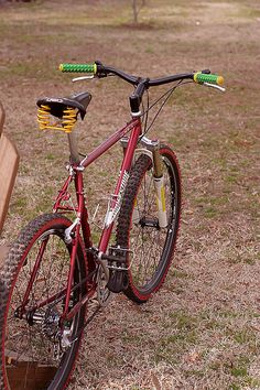 a red bike parked next to a wooden bench