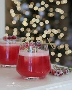 two glasses filled with liquid sitting on top of a table next to a christmas tree